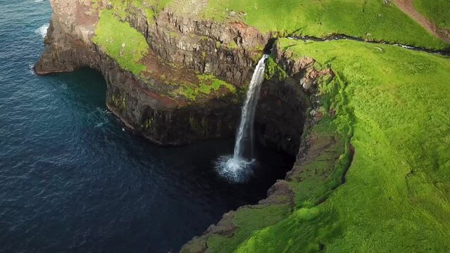 Aerial view of Mulafossur waterfall, Faroe Islands. Small village Gasadalur with a Hvannadalur valley. Sunny day in summer. High quality 4k footage.