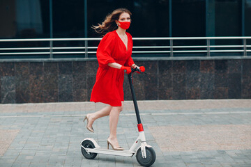 Young woman with electric scooter in red dress and gloves with face mask at the city. New normal...