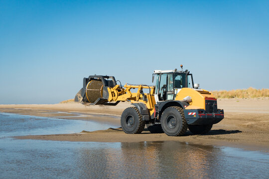 Excavator cleaning a beach from seaweed and algae, by using a customized truck.