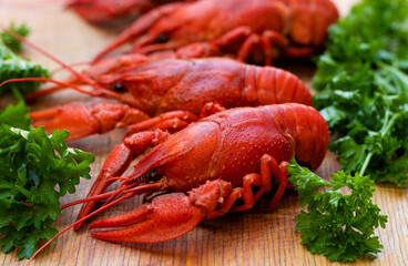 Boiled red crayfish or crawfish with parsley on a wooden kitchen board close-up. Menu for a pub or restaurant. Selective focus