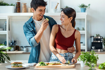 Lovely young couple cooking together while having a goos time in the kitchen at home.
