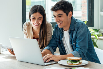 Beautiful lovely couple using their laptop and digital tablet to searching voyage in the kitchen at home.