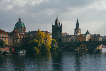 Fototapeta na wymiar view of the Charles Bridge and the architecture of the old town of Prague, Czech Republic. Boats on the river. Beautiful old town in autumn