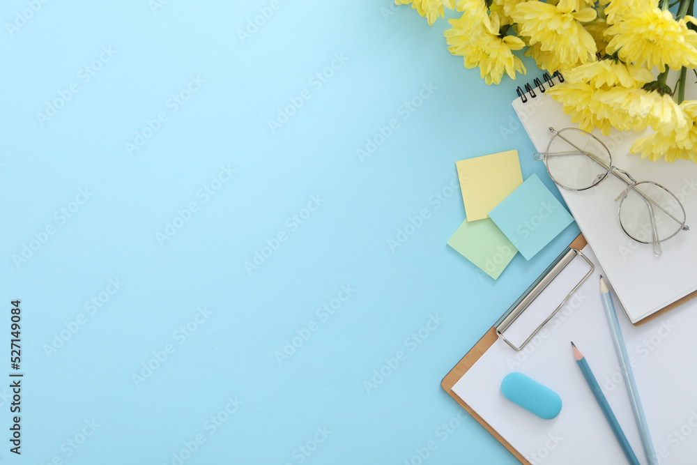 Wall mural Beautiful flowers and stationery on light blue background, flat lay with space for text. Teacher's Day