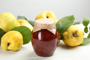 Delicious quince jam and fruits on white wooden table, closeup