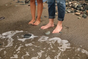 Young couple on sandy beach near sea, closeup