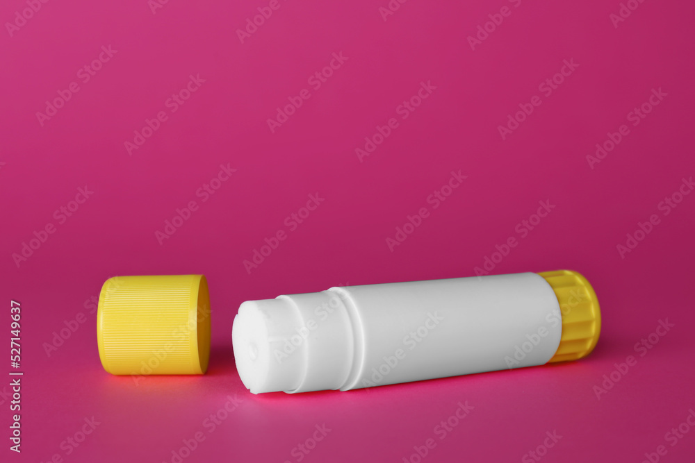 Poster blank glue stick and cap on fuchsia background, space for text