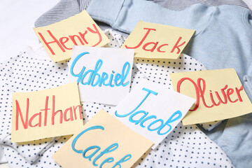 Many sticky notes with different baby names on child's clothes, closeup