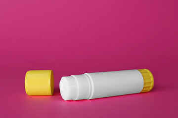 Blank glue stick and cap on fuchsia background, space for text