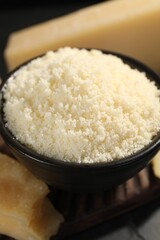 Bowl with grated parmesan cheese on table, closeup