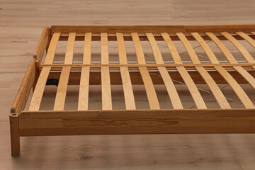 Wooden bed frame on floor, closeup view