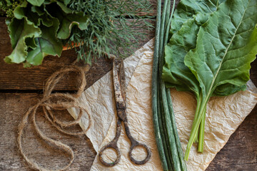 Flat lay composition with different herbs and rusty scissors on wooden table