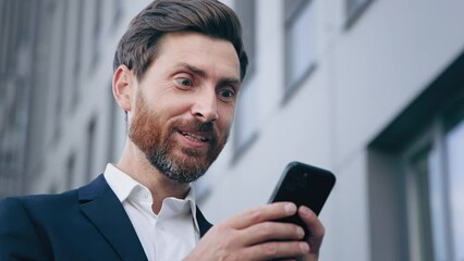 Close-up young surprised man looks at phone screen receiving notification reading good news rejoicing in success satisfied businessman gets excellent result from sales profitable offer salary increase