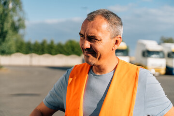 Fototapeta premium Portrait of caucasian mature man on semi-truck vehicles parking background. Truck driver worker 