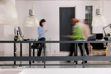 Diverse employees silhouettes walking in business coworking space, long exposure effect. Blurred...