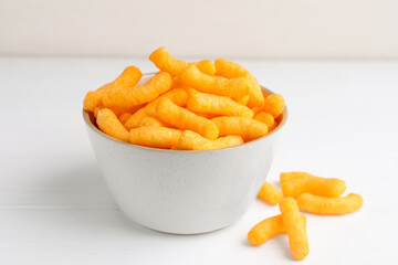 Bowl with crunchy cheesy corn snack on white table, closeup