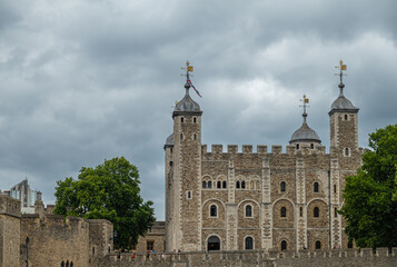 Fototapeta na wymiar London, England, UK - July 6, 2022: Tower of London. White tower palace building seen over ramparts from Thames River under gray cloudscape.
