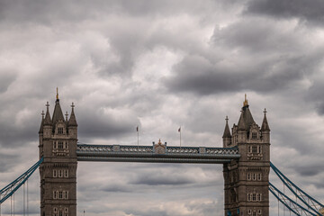 Fototapeta na wymiar London, England, UK - July 6, 2022: Top half of Tower bridge seen from up brown water Thames on Western side under thick gray cloudscape.
