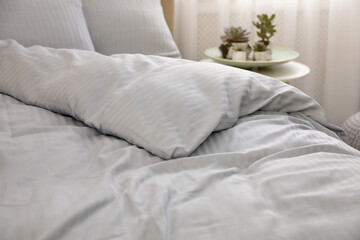 Fototapeta na wymiar Comfortable bed with soft blanket indoors, closeup