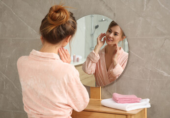 Beautiful woman wearing pink bathrobe in front of mirror at home - obrazy, fototapety, plakaty