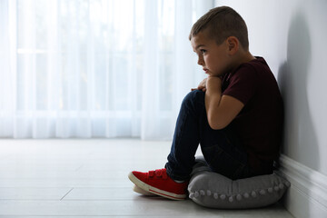 Sad little boy near white wall indoors, space for text. Domestic violence concept - obrazy, fototapety, plakaty