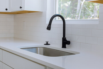 With new kitchen cabinets installed, a view of the water tap sink in a kitchen can be seen