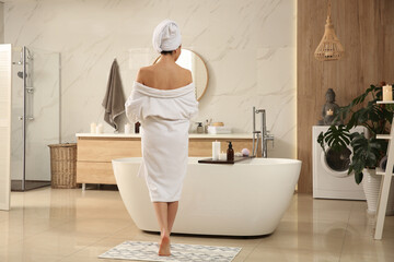 Young woman near tub in bathroom, back view