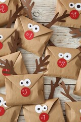Set of gifts in envelopes with deer faces on white wooden table, flat lay. Christmas advent calendar