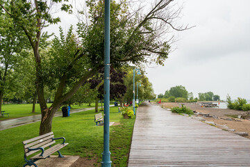 People walk along a wooden boardwalk beside Woodbine Beach on a rainy afternoon in Toronto's...