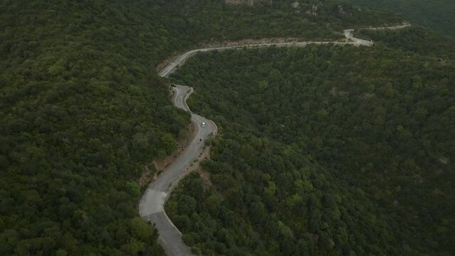 Drone flights in top of a road in the middle of a green forested hill, some cars and people are using the road, filmed in Margalla hills, Islamabad Pakistan, aerial 4 k