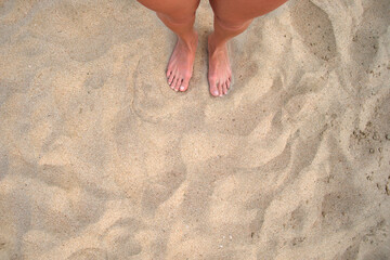 Fototapeta na wymiar Female bare feet standing on beach sand