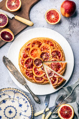 Sliced Blood Orange Cake, with layered citrus, on white platter, with cutting board and cut blood...