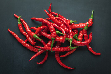 Top view of a bunch of red ripened 'Ring of Fire' hot cayenne chili peppers on a black background