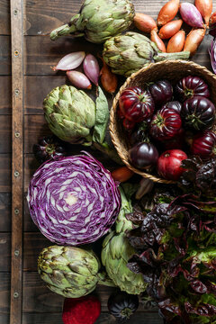 violet vegetables on the wooden background, purple artichoke, tomatoes, oniones, salad