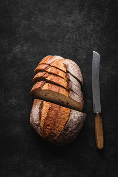 Rustic sliced sourdough loaf with bread knife.