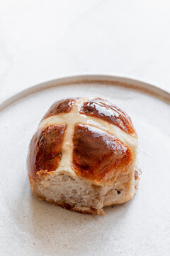 Hot cross bun on a ceramic plate.