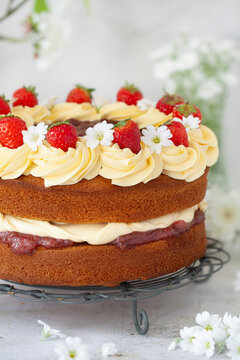 A sponge cake filled with cream and cream then toped with strawberries and white flowers.