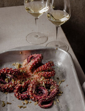 Fresh octopus marinated with spices, garlic and tomatoes on gray table
