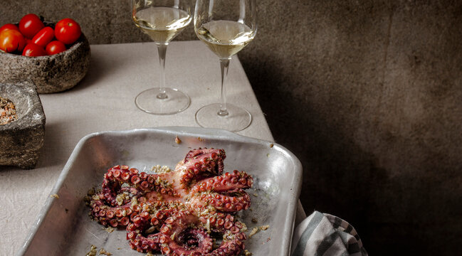 Fresh octopus marinated with spices, garlic and tomatoes on gray table
