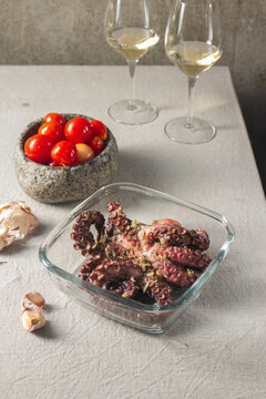 Fresh octopus marinated with spices, garlic and tomatoes on gray table