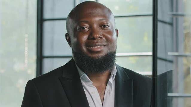 Positive african american businessman male team leader general manager banker lawyer handsome adult 40s bearded man wears black formal suit friendly looking at camera smiling posing in modern office
