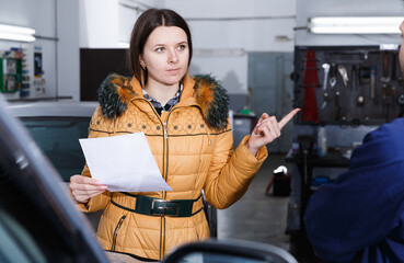 Fototapeta na wymiar Woman client is dissatisfied of repair of her car in winter in workshop.