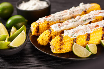 Roasted or grilled sweet corn cobs with with cream sauce, lime and cilantro, selective focus....