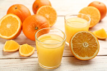 Delicious orange juice and fresh fruits on white wooden table, closeup