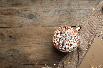 Cup of delicious hot cocoa with marshmallows on wooden table, flat lay. Space for text