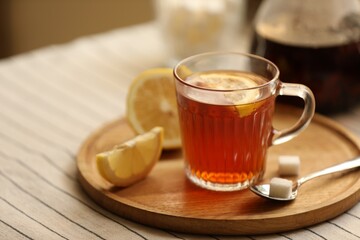Glass mug of aromatic tea with lemon and sugar on table, closeup. Space for text