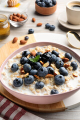 Tasty oatmeal porridge and ingredients served on wooden table. Healthy meal