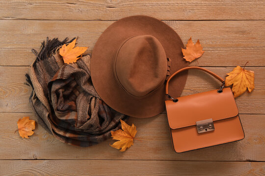 Flat lay composition with hat and dry leaves on wooden background. Autumn season