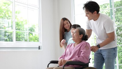 Happy asian family feel excitement moving to new house, Father, mother and daughter take care grandmother support moving wheelchair seeing around on moving day.