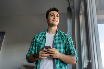 One man standing at home using mobile phone to send messages or call